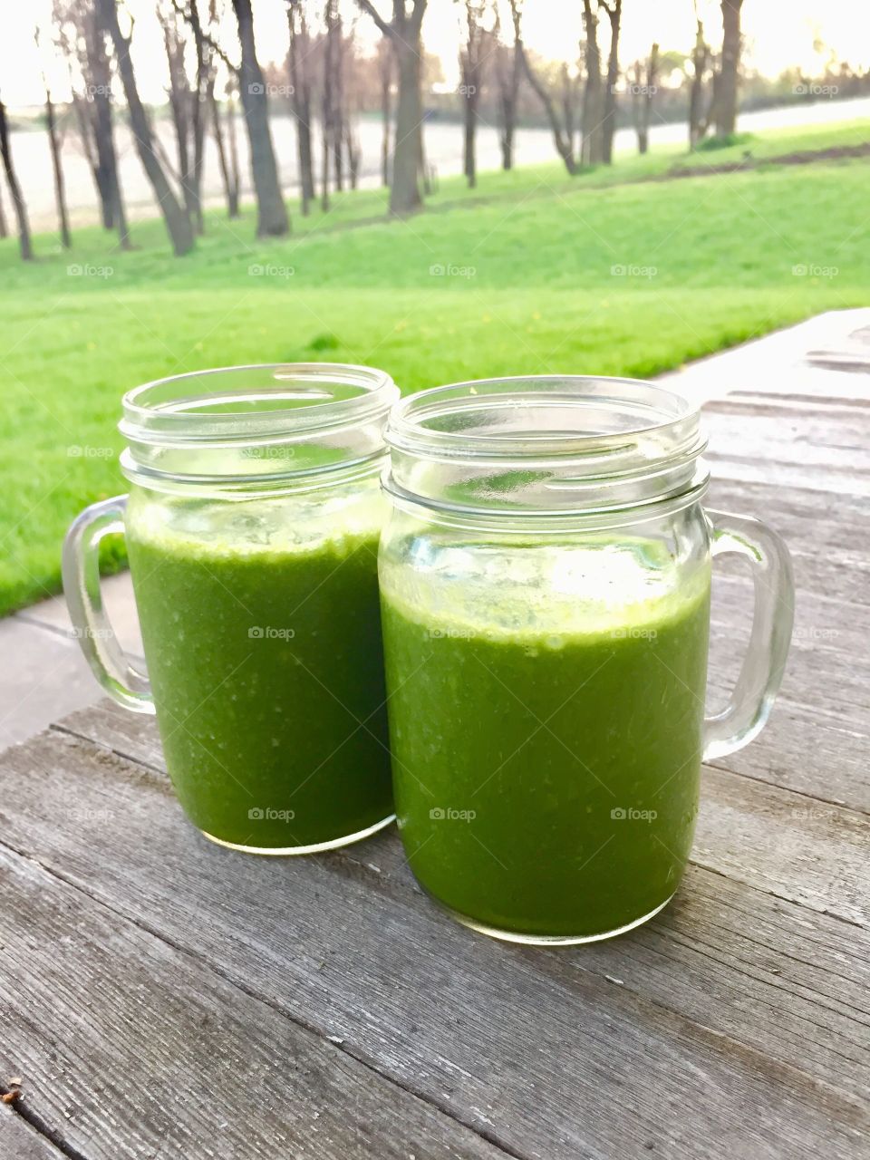 Green Color Story - green smoothies on a wooden porch against a green grass background 