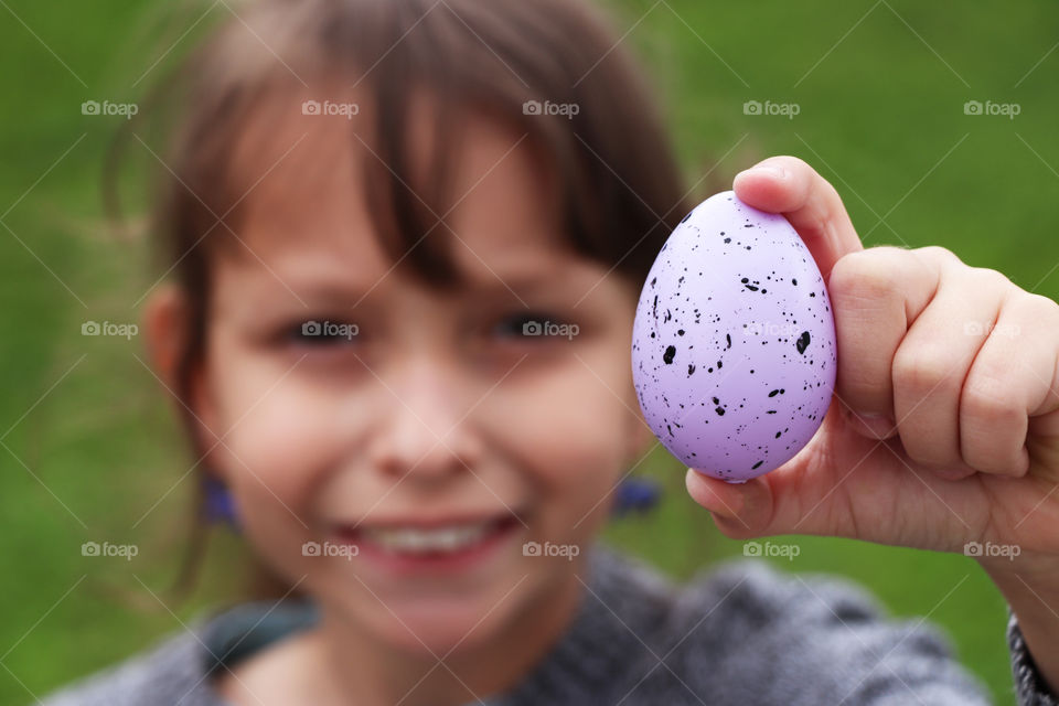 Child holding a purple Easter egg in her hand