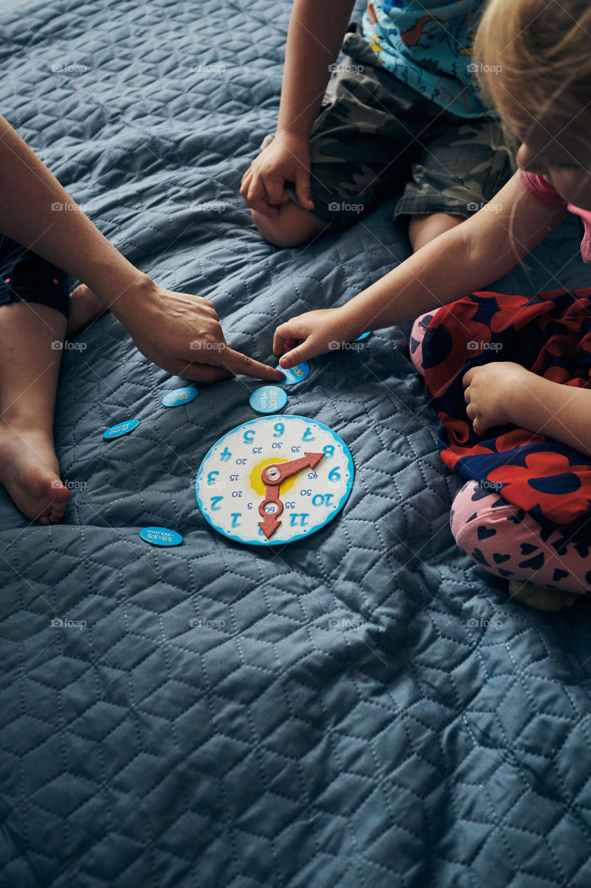 Kids learning how to tell time from clock and set the hands in the correct position. Teaching preschoolers tell time. Candid people, real moments, authentic situations