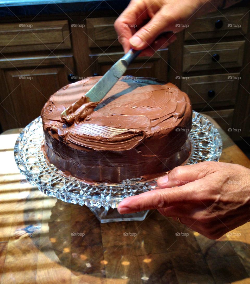 Traditional American Dishes. Hands frosting homemade chocolate cake on Waterford Crystal cake dish!