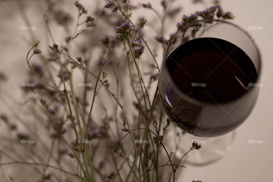 A glass of red wine, dried flowers 