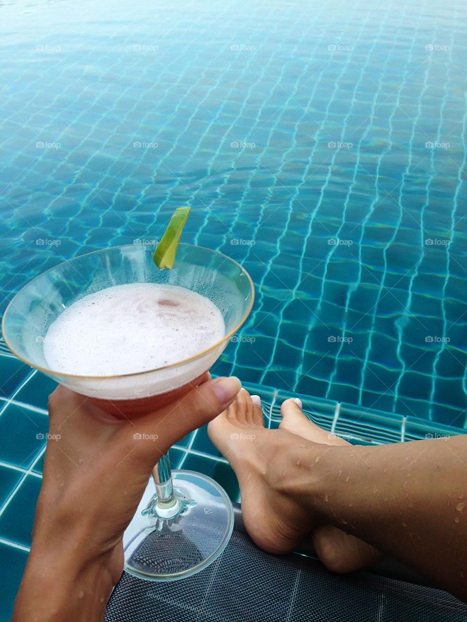 Enjoying alcoholic beverages by swimming pool during tropical vacation in lazy summer days 