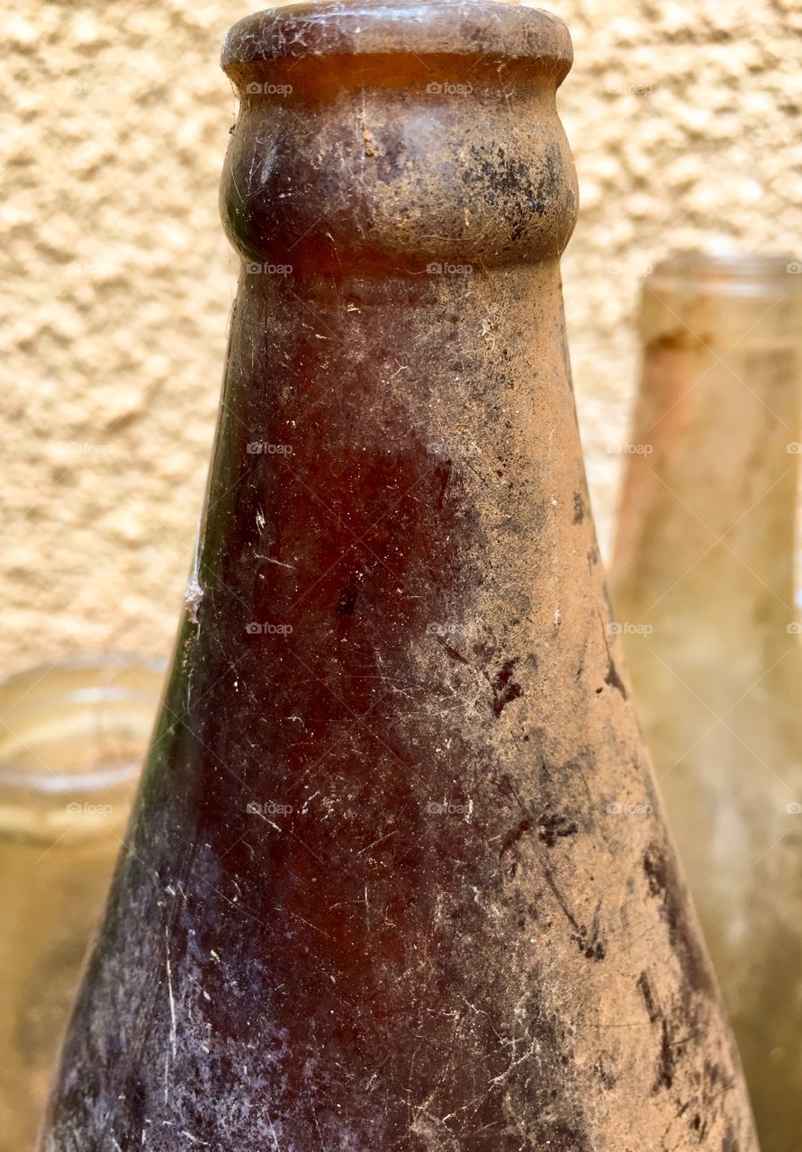 Closeup view freshly unearthed brown glass antique vintage bottle upright outdoors 