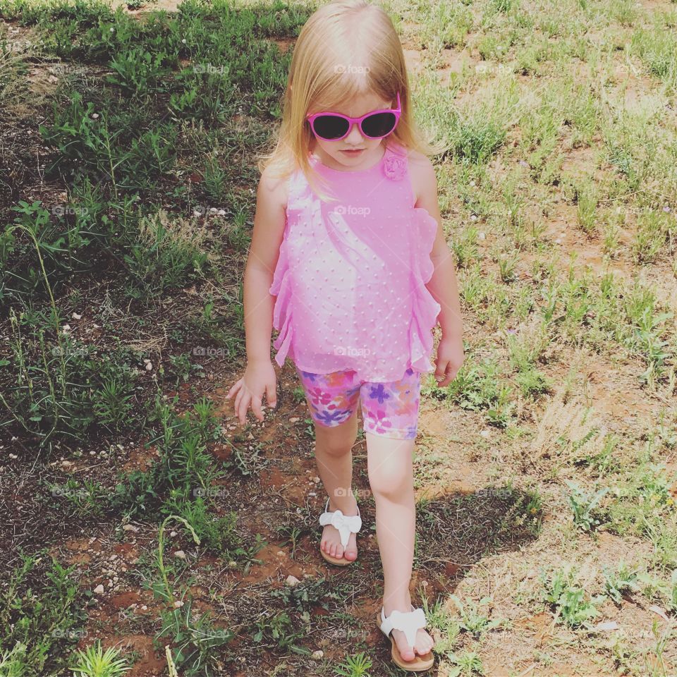 Little girl walking outside in the green grass.