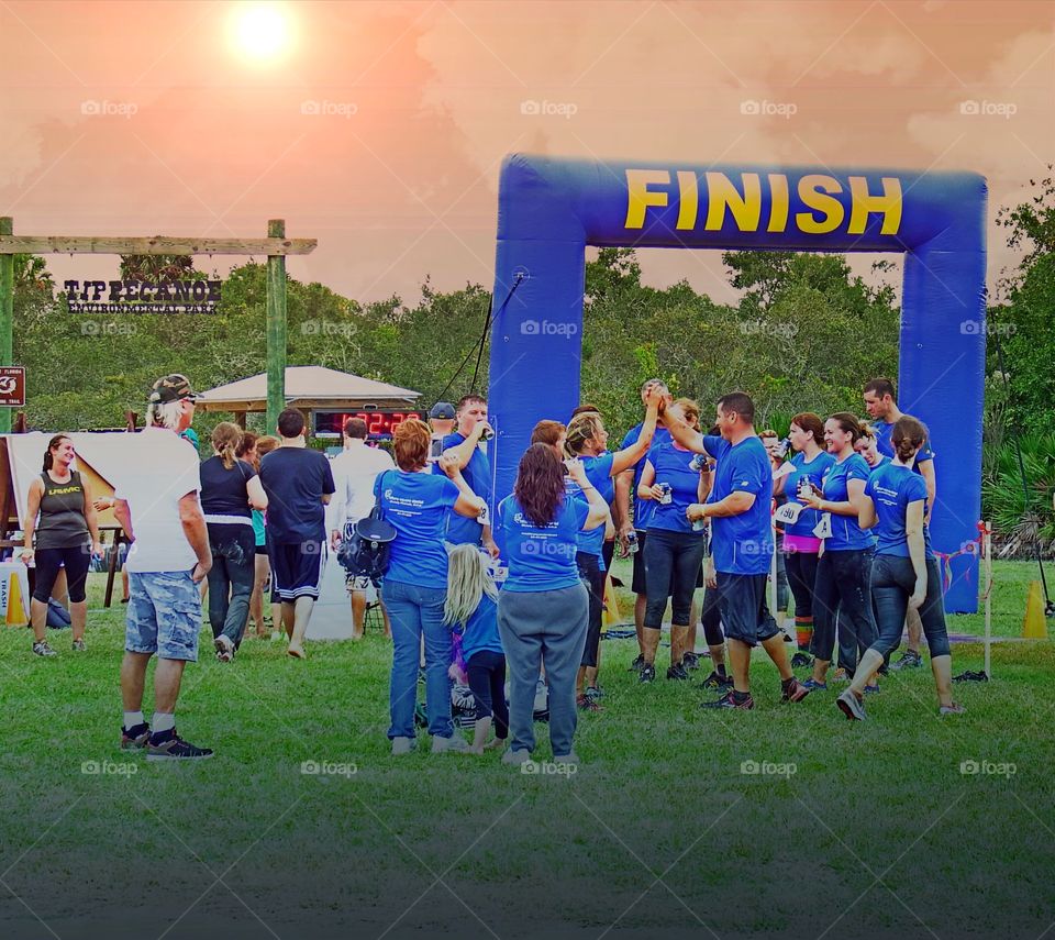 Joggers celebrate at the finish line of a road race on a hot summer day.