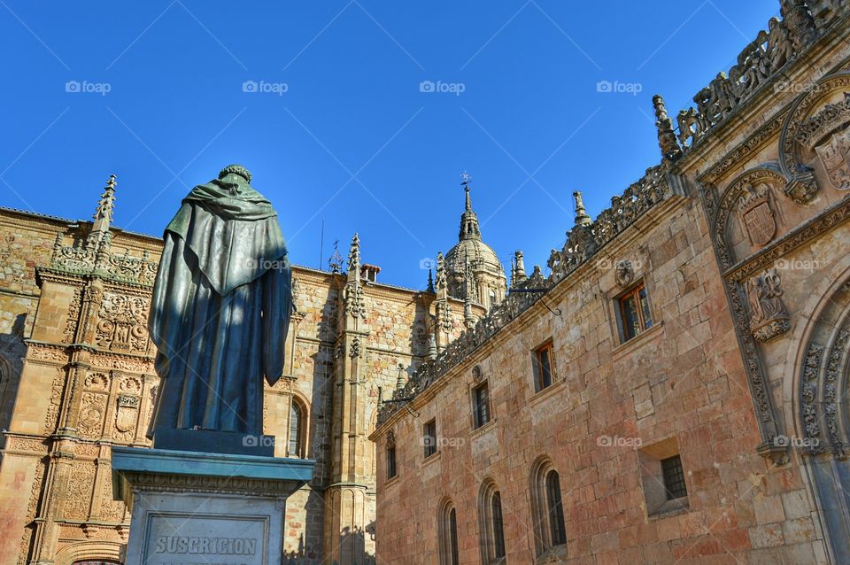 University of Salamanca. Building of University of Salamanca. Statue of Fray Luis de León in the foreground and cathedral tower in the background