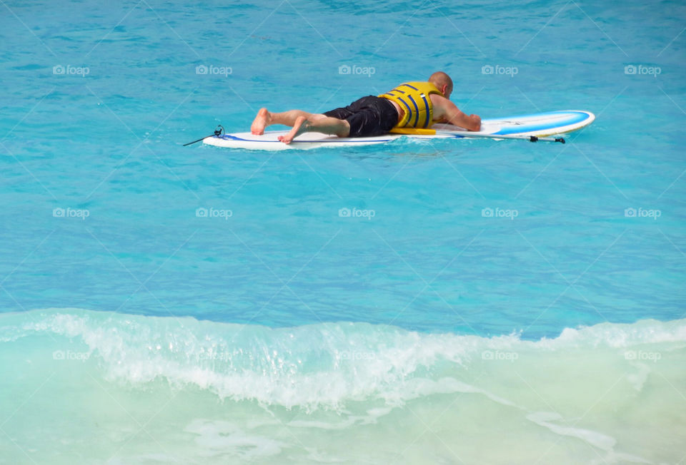 A surfer waiting to catch some waves on his long board