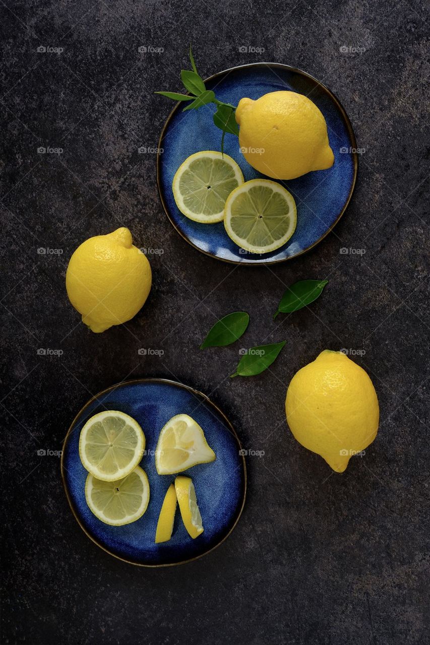 Directly above view of lemons on blue plates isolated on dark table. 