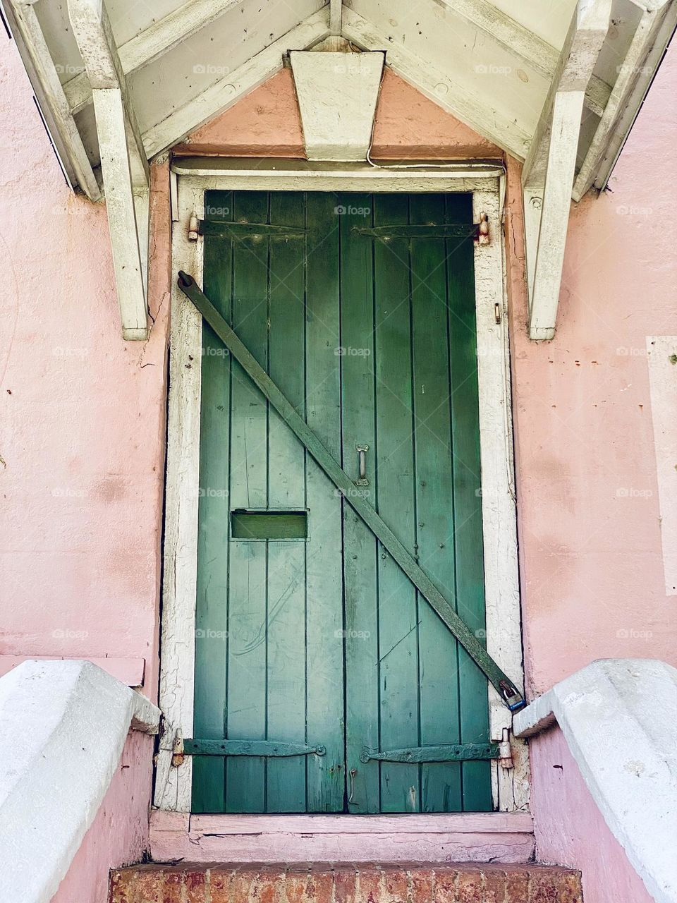 A green door in a pink building