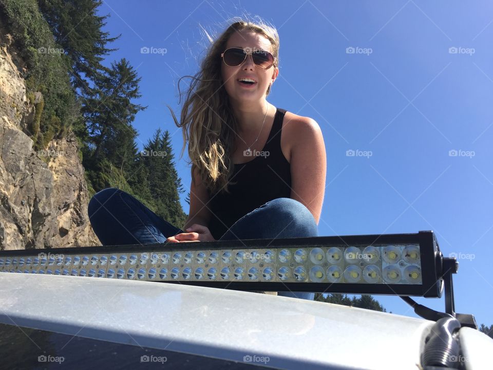 Young woman sitting on top of car