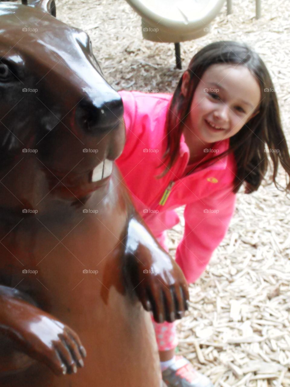 Peekaboo . Little girl looking out from behind a giant beaver. 