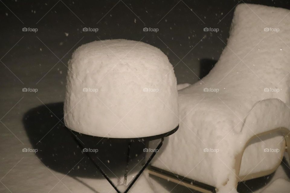 Fresh snow piled on a tabletop and chair 