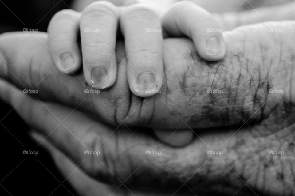 This photo shows a grandpa holding his newborn granddaughters hand