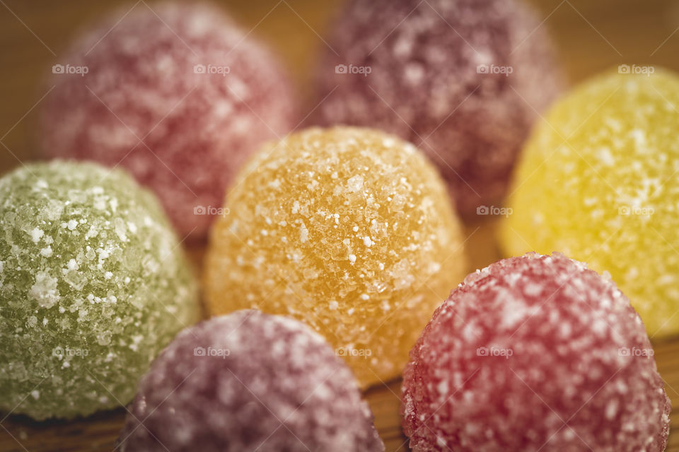 A close up portrait of a piece of candy sprinkled with sugar and surrounded by similar pieces of candy.