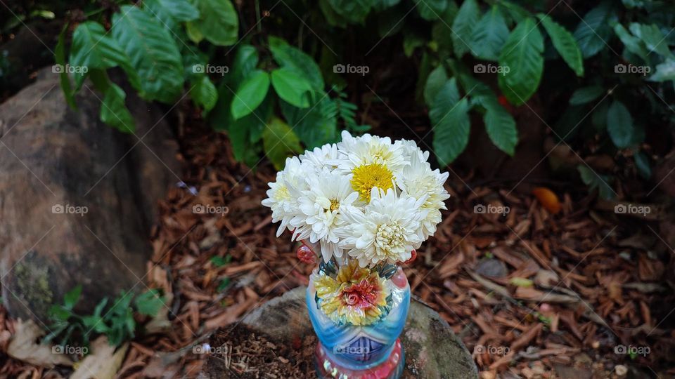 Beautiful white flowers in a colourful flowerpot with a flower sculpture, Flowers in a vase, colourful vase, white flowers in a vase