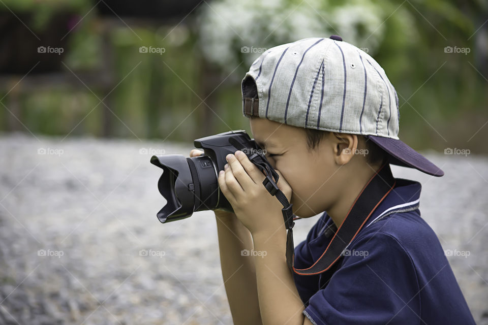 Hand boy holding the camera Taking pictures in park.