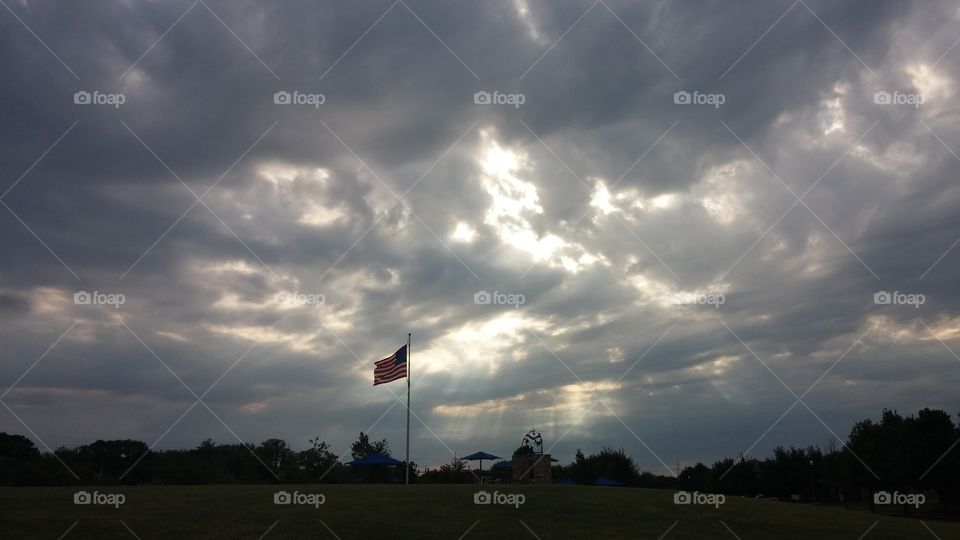 God and America. sin rays shining down on American Flag