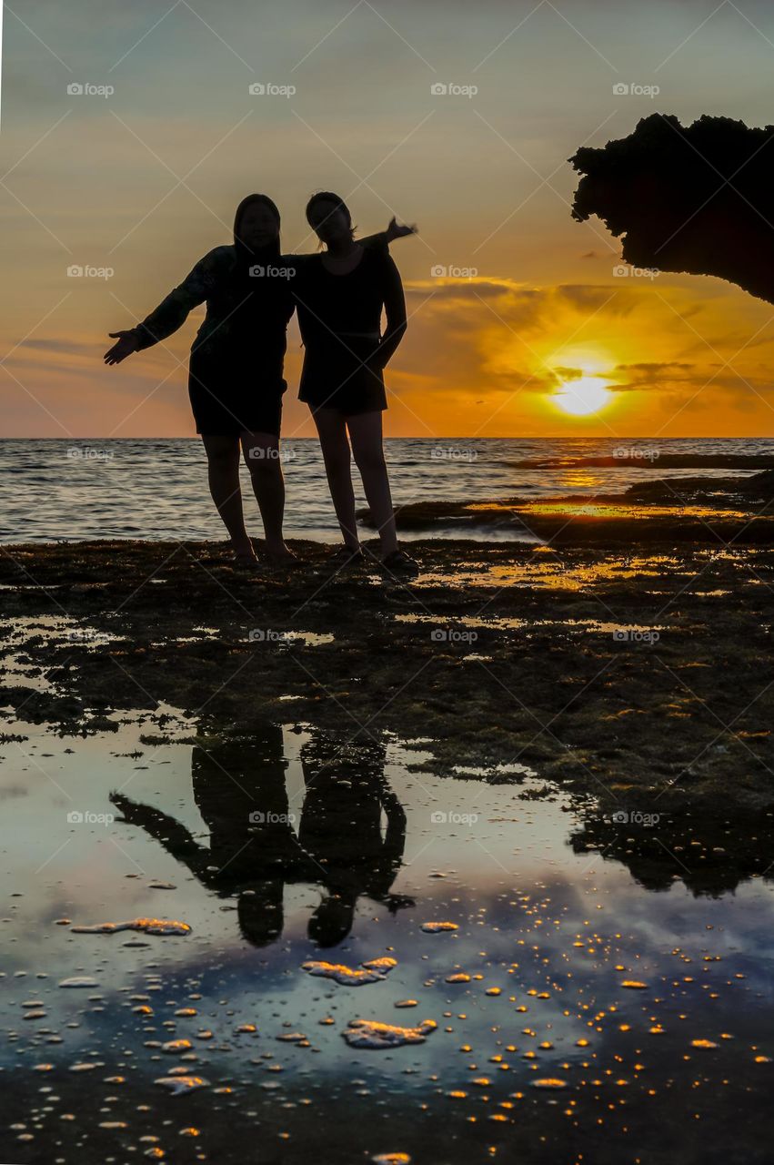 Silhouette of two people along the beach at sunset