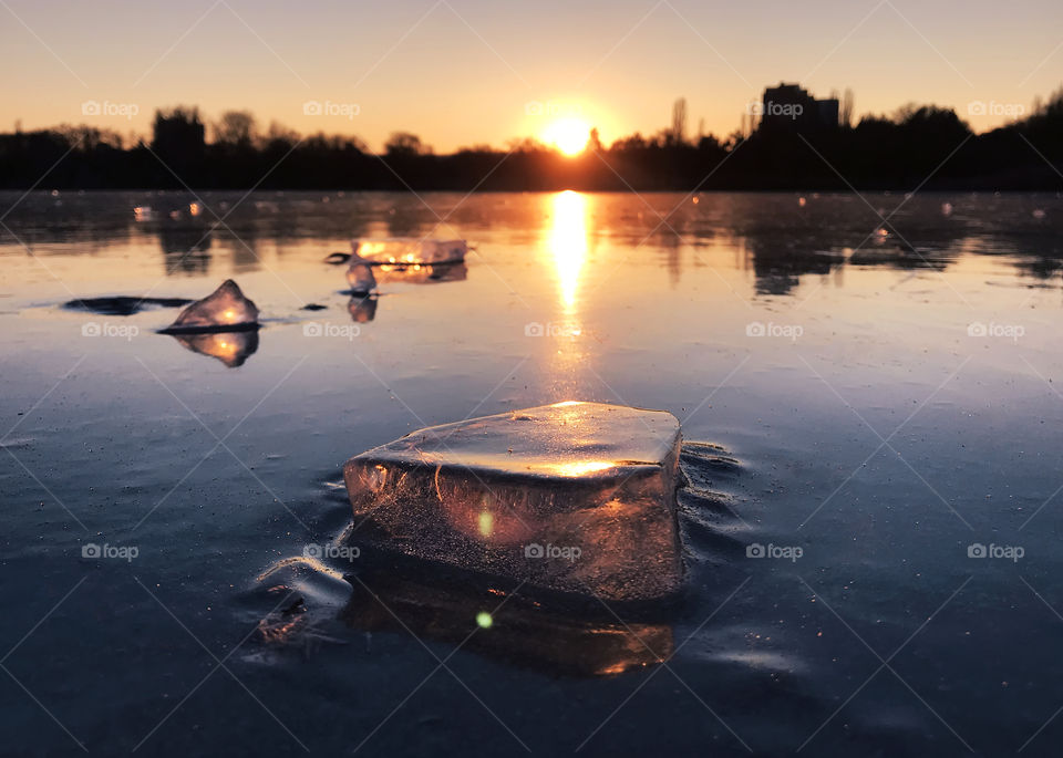 Pieces of ice at sunset on frozen lake in winter 