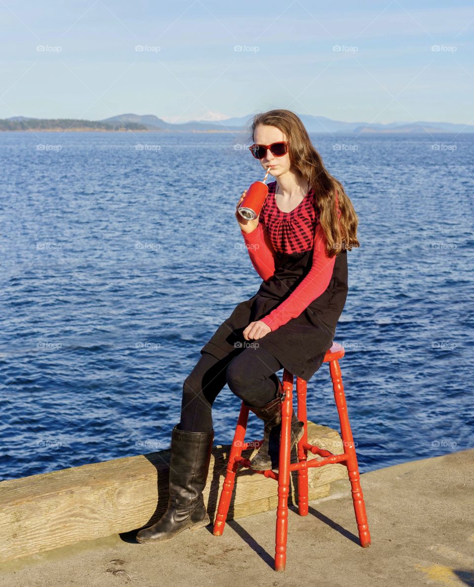 Girl in red on red stool drinking red drink