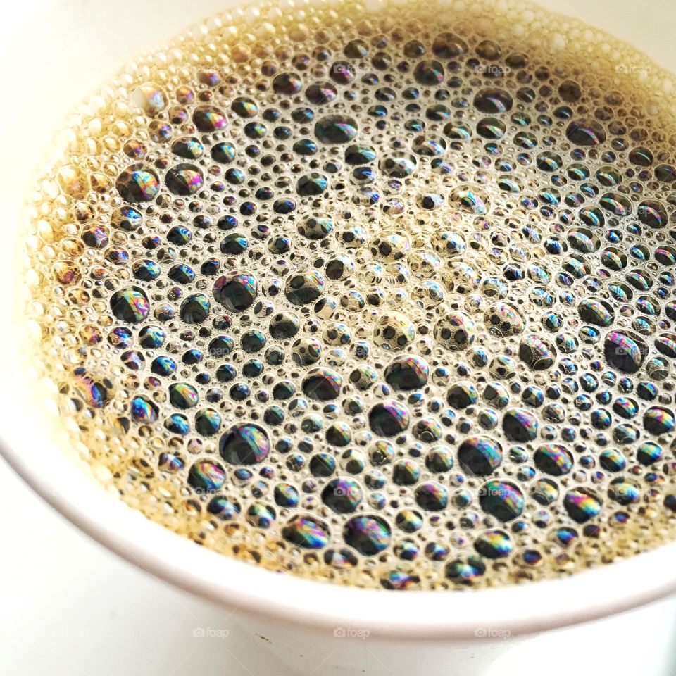 Shot of frothy black coffee in cup