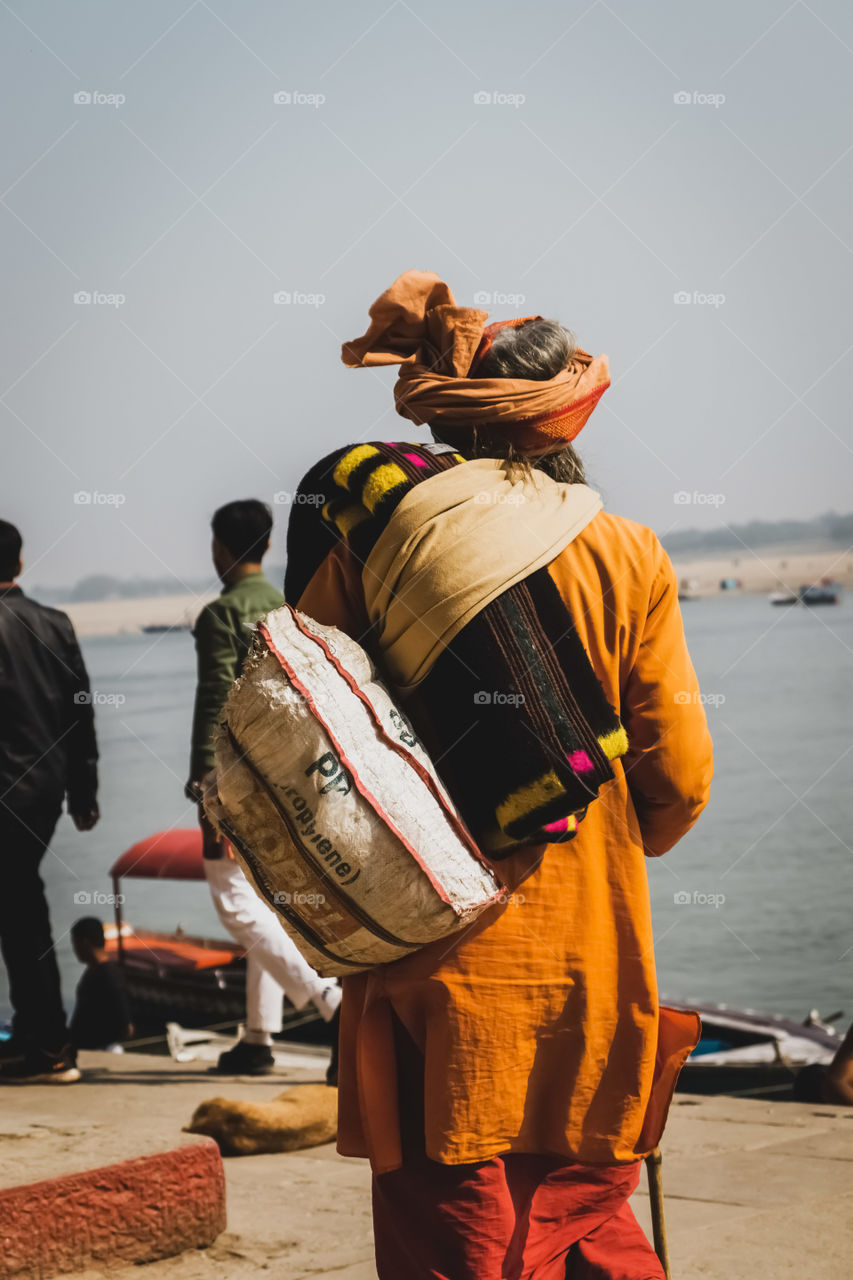 Man Walks Towards Boat Photo
A man wearing an orange turban walks towards the river's edge where a boat awaits.