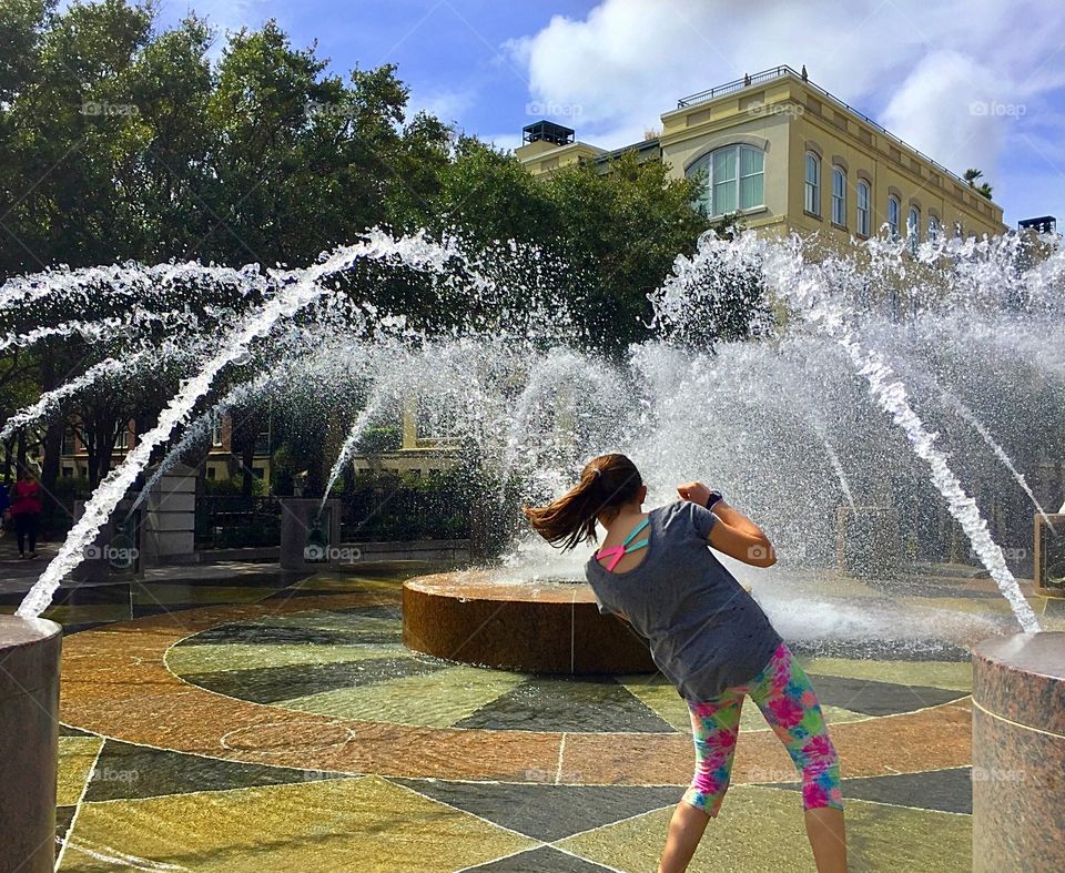 Young girl plays in outdoor tiled fountain in downtown Charleston, South Carolina. 
