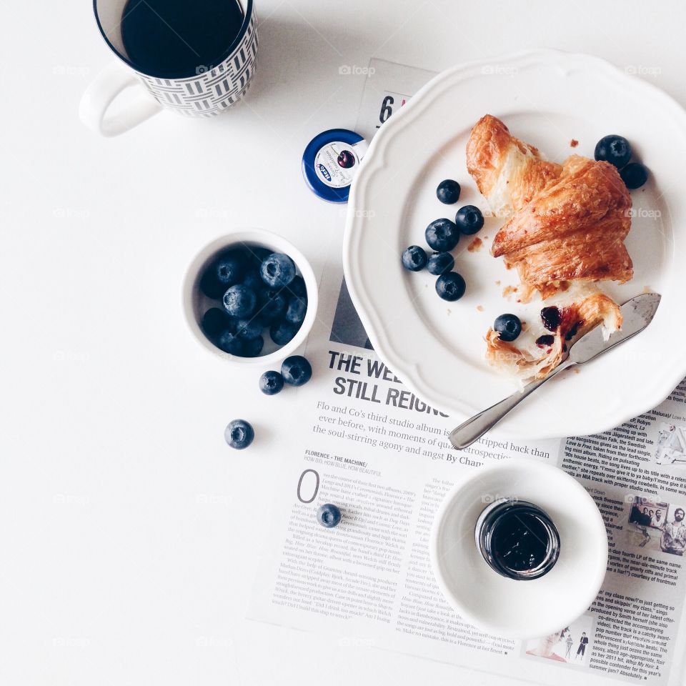 Simply breakfast with wholewheat croissant, blueberries and black coffee.