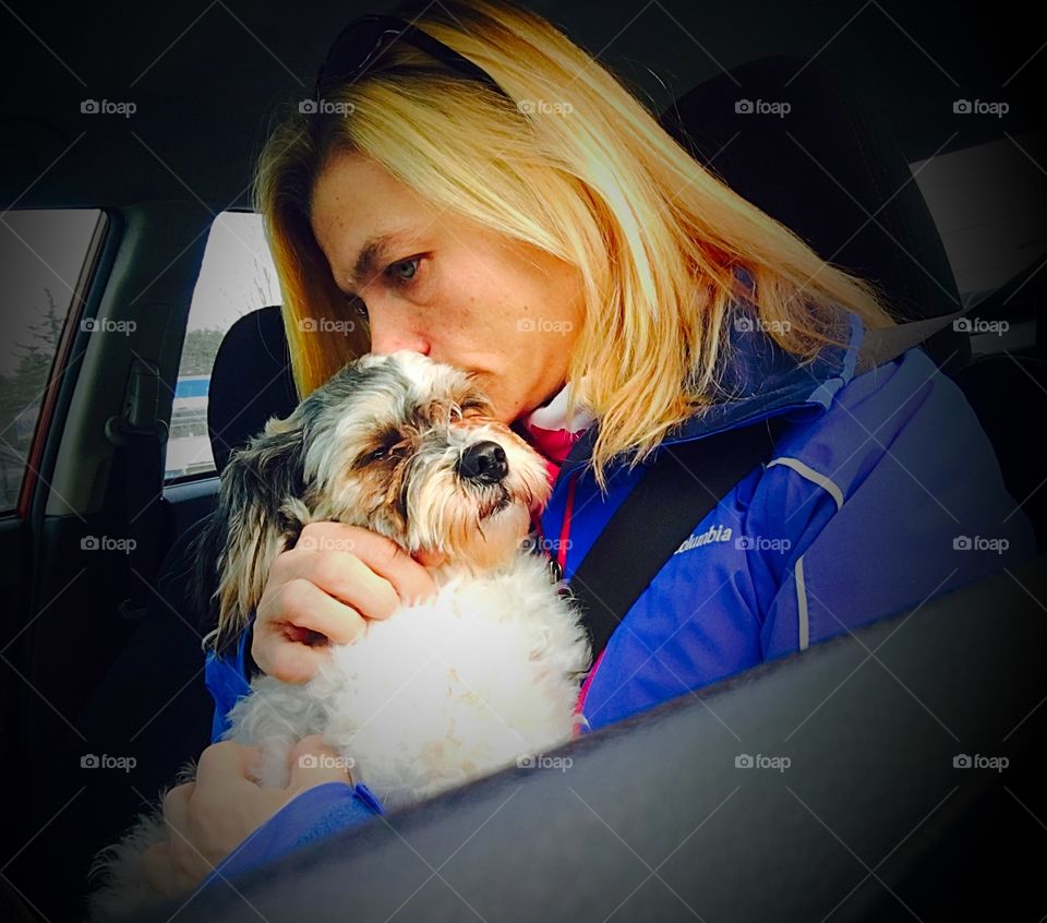 Woman sitting in car loving her dog