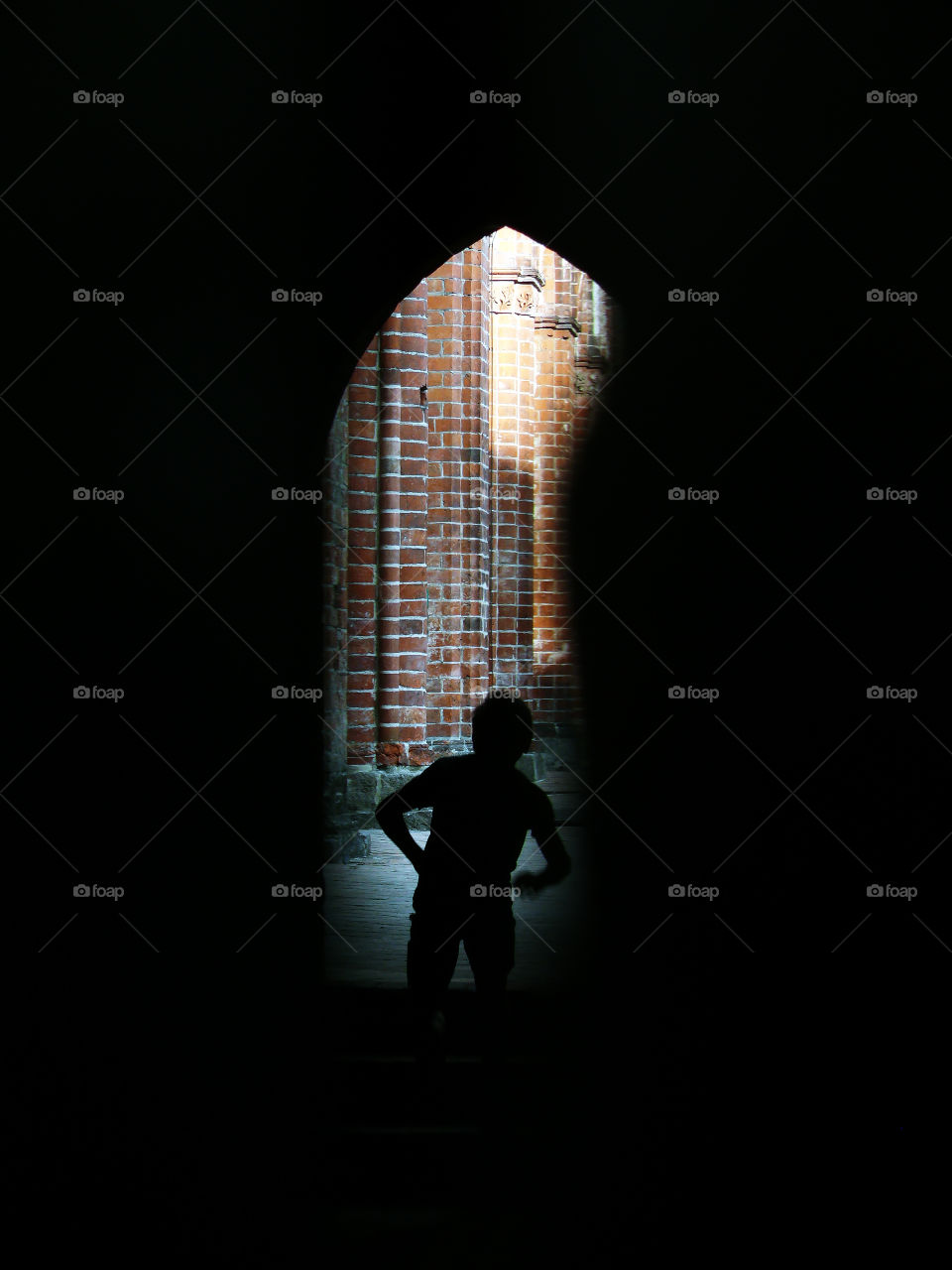 Silhouette of boy running upstairs seen through a hole in the wood in Chorin, Germany.