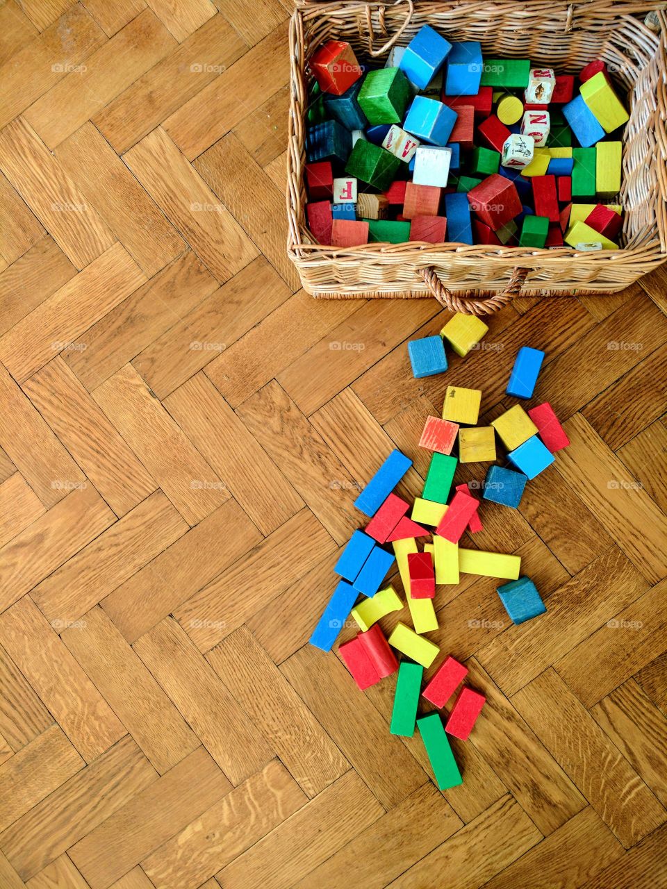Child's toy coloured wooden building blocks/bricks splicing out of a basket.