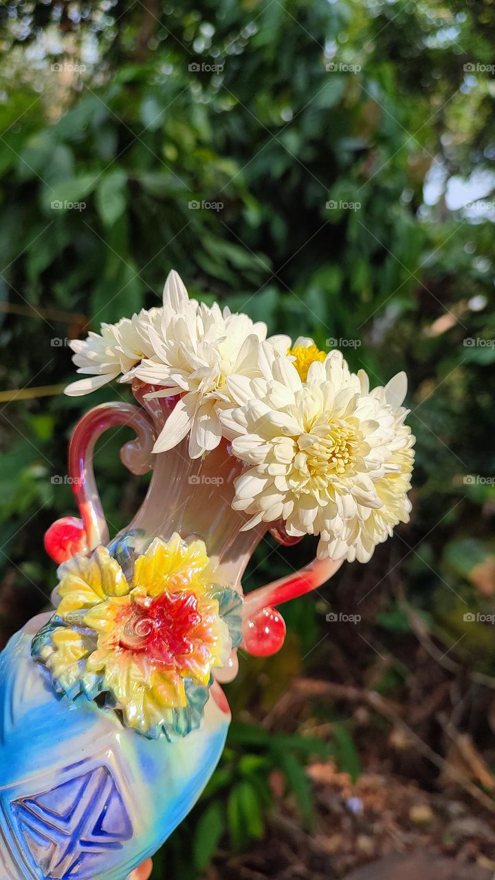 Beautiful white flowers in a colourful flowerpot with a flower sculpture