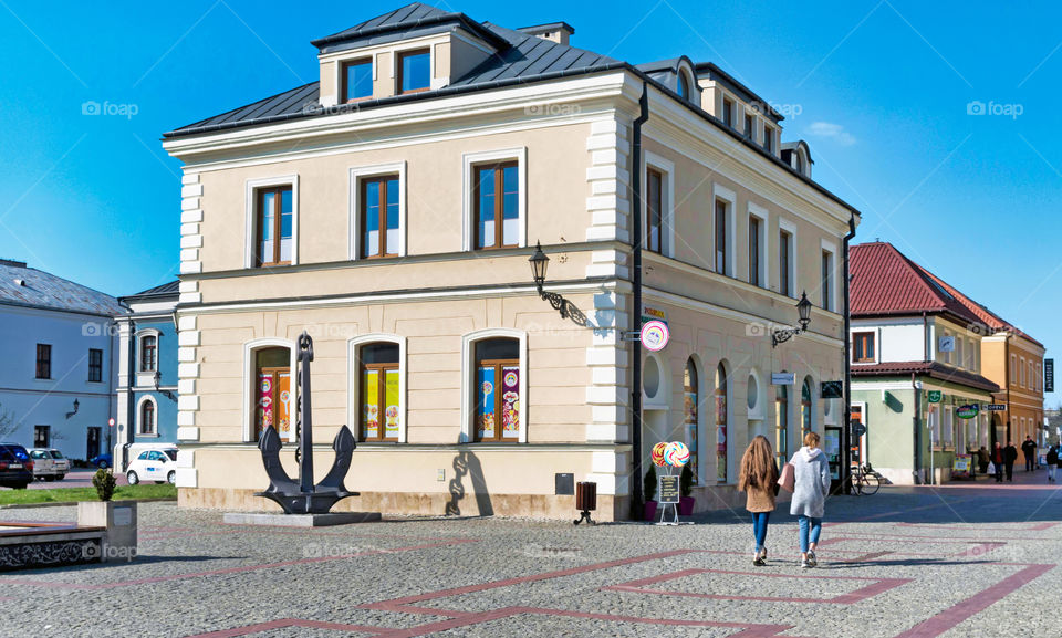 People walking on Solny Market against buildings in Zamość, Poland.