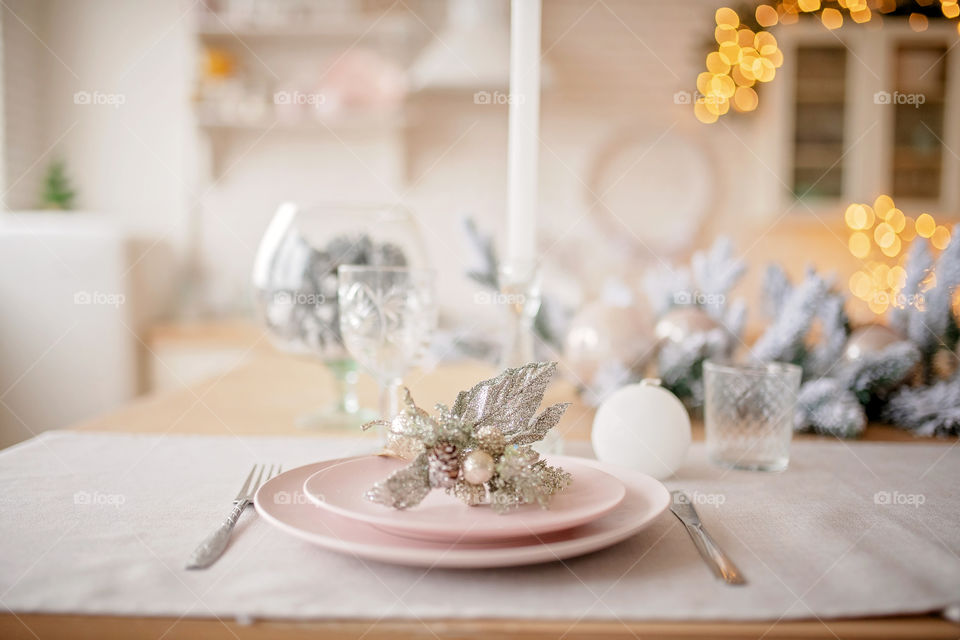 Festive winter cozy kitchen interior with garlands, decorations and gifts.  Christmas dinner at the decorated table.