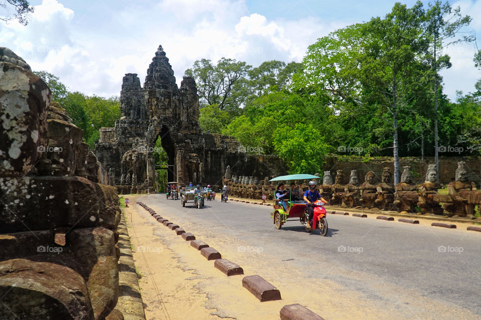 tuk tuk passing through south gate of angkor thom