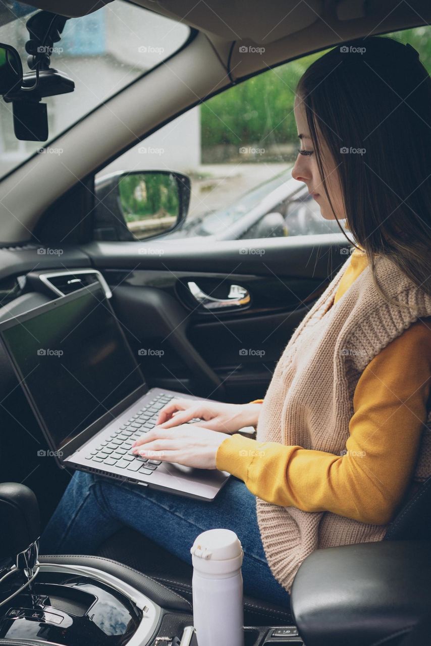 Young woman watching movie on laptop in car