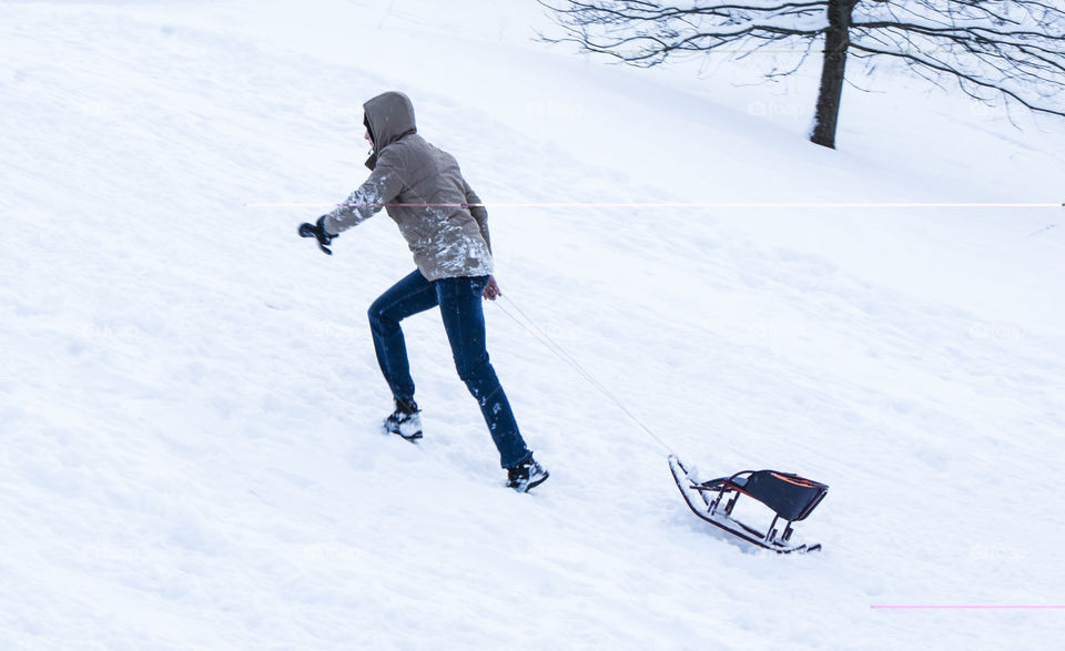 a man goes uphill and carries a sled