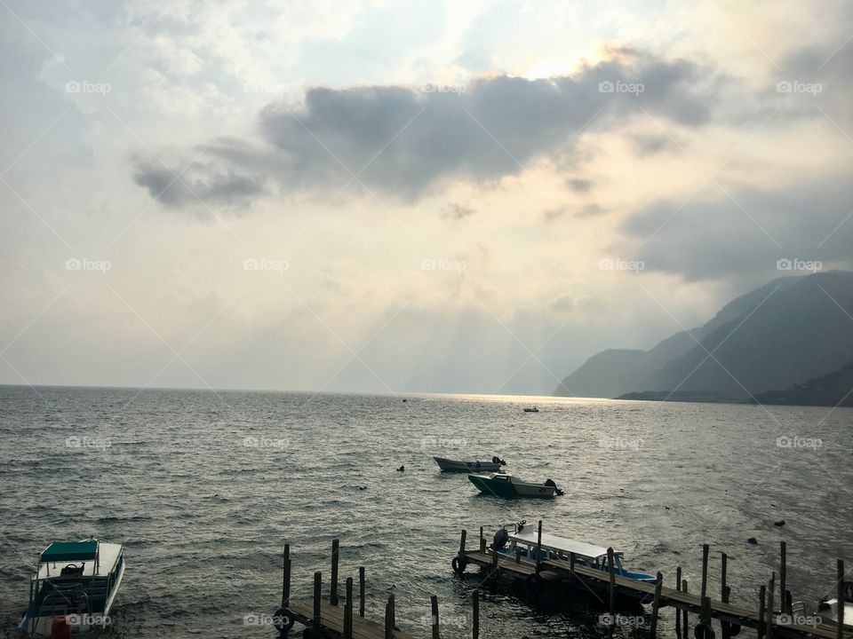 Rays of sunlight shoot out from behind the clouds on the lake