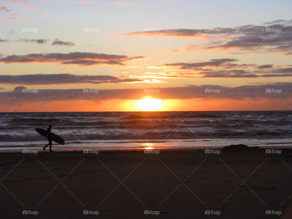 Surfer carrying surfboard on the beach