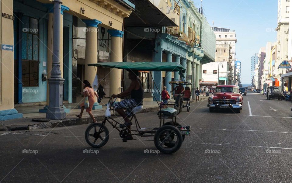 Rickshaw and American car on the same street in Havana