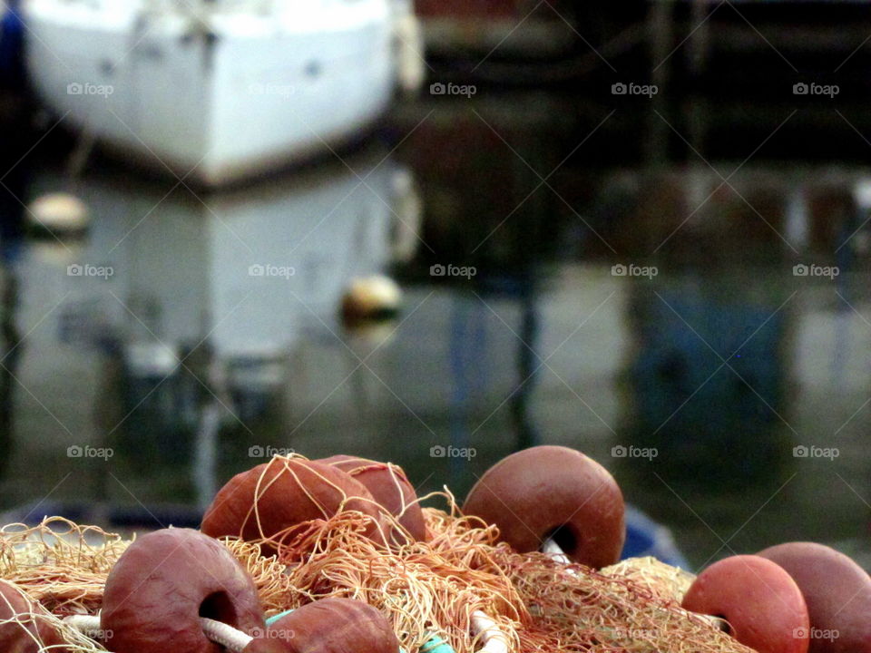 boat reflection in the harbor water with fishing nets in the foreground