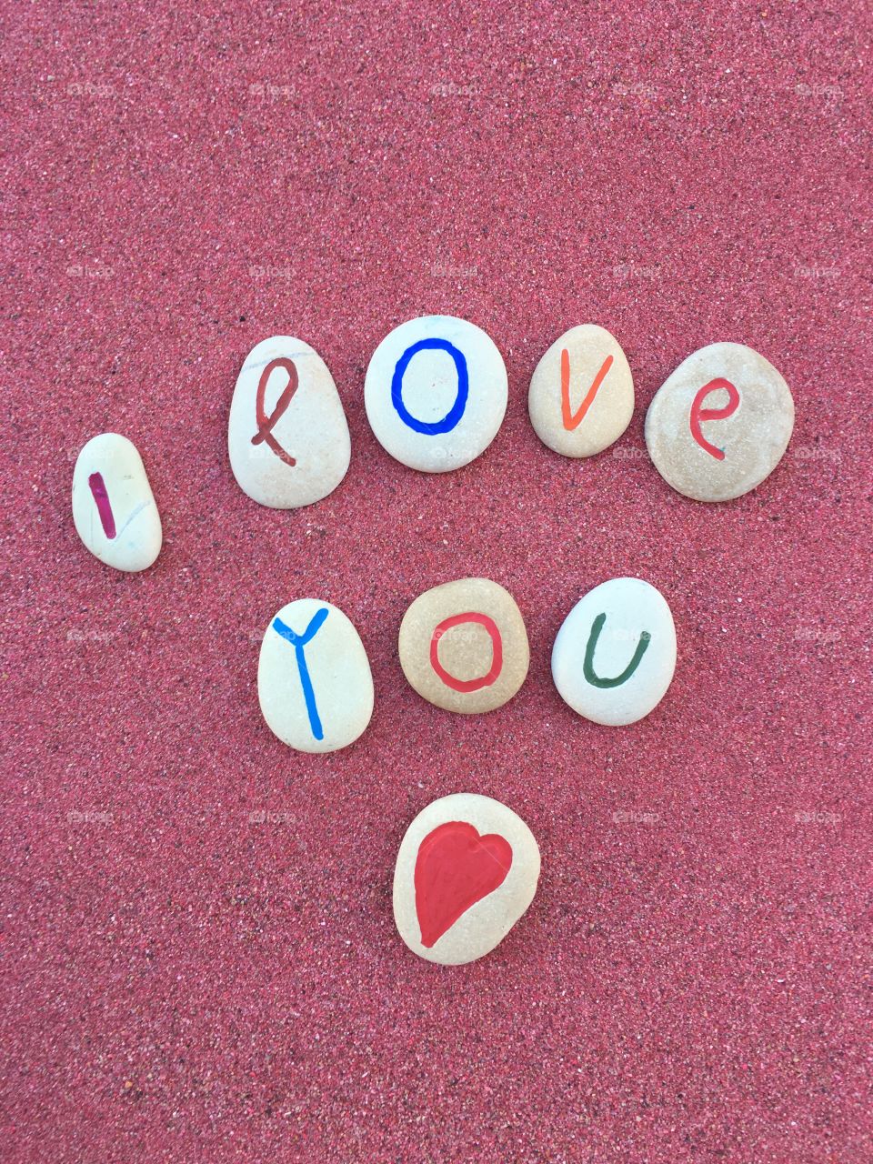 I love you message with stone letters on red sand