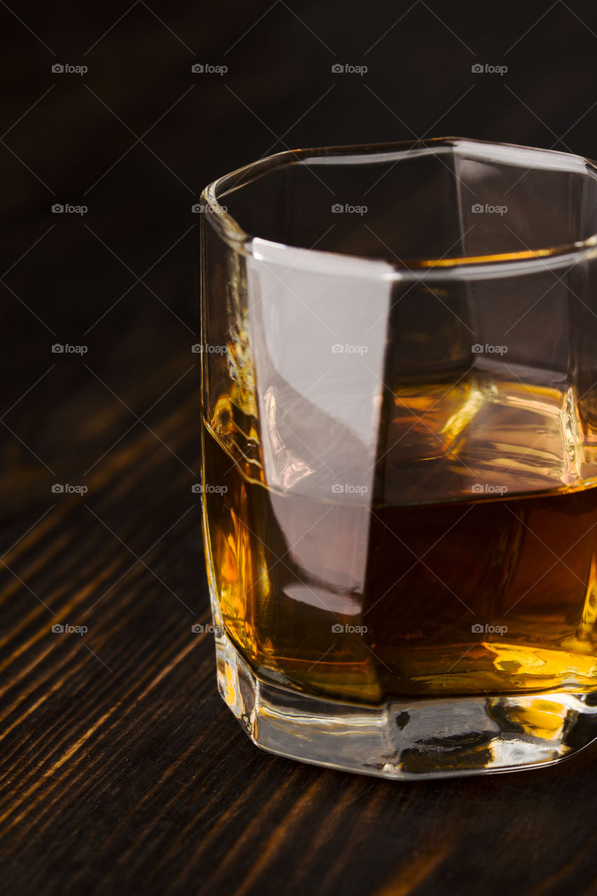 glass of whiskey on dark wood background