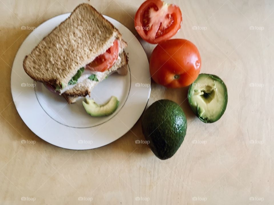 Prepared healthy turkey sandwiches on wheat bread with sliced turkey, avocado, and tomatoes 