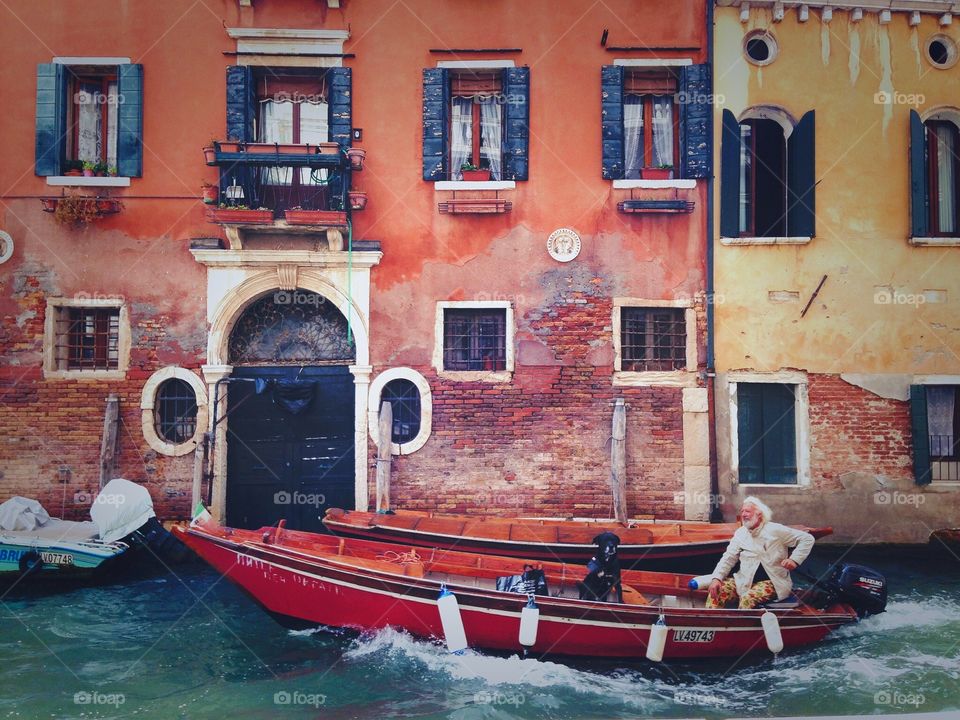 Man with his dog friend having walk in gondola down the canal in Venice. 