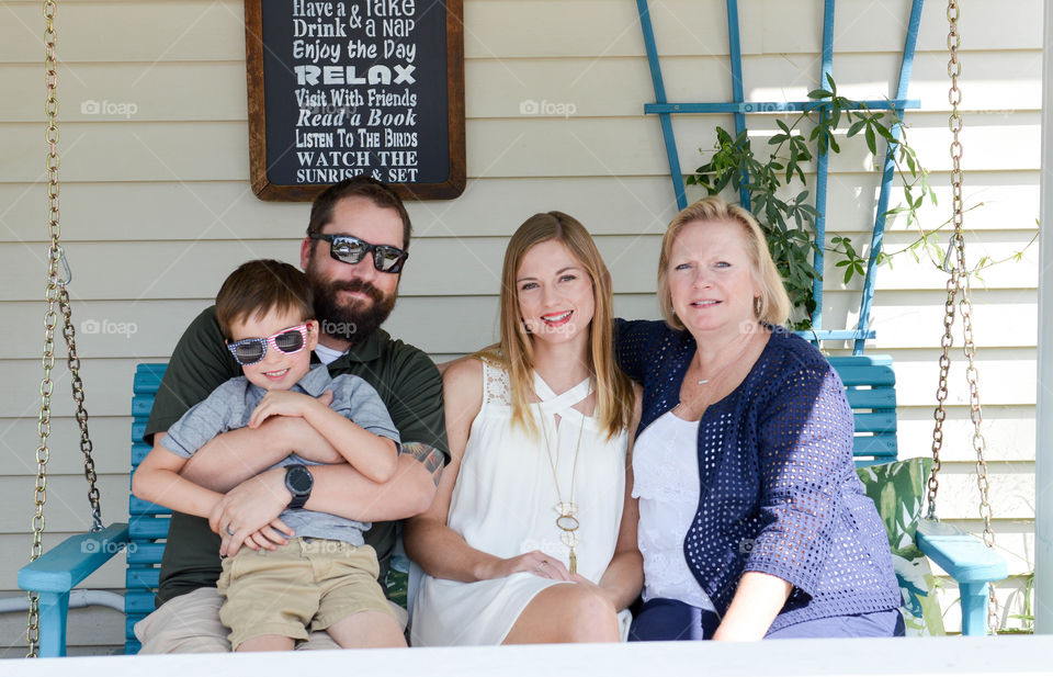 Family portrait on a porch bench swing outdoors on a sunny summer day