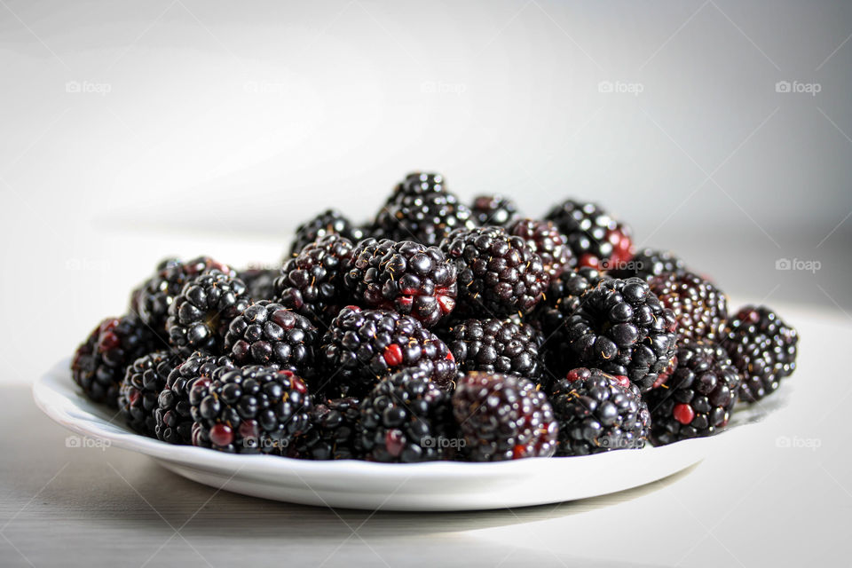 Gorgeous ripe blackberries on a white plate