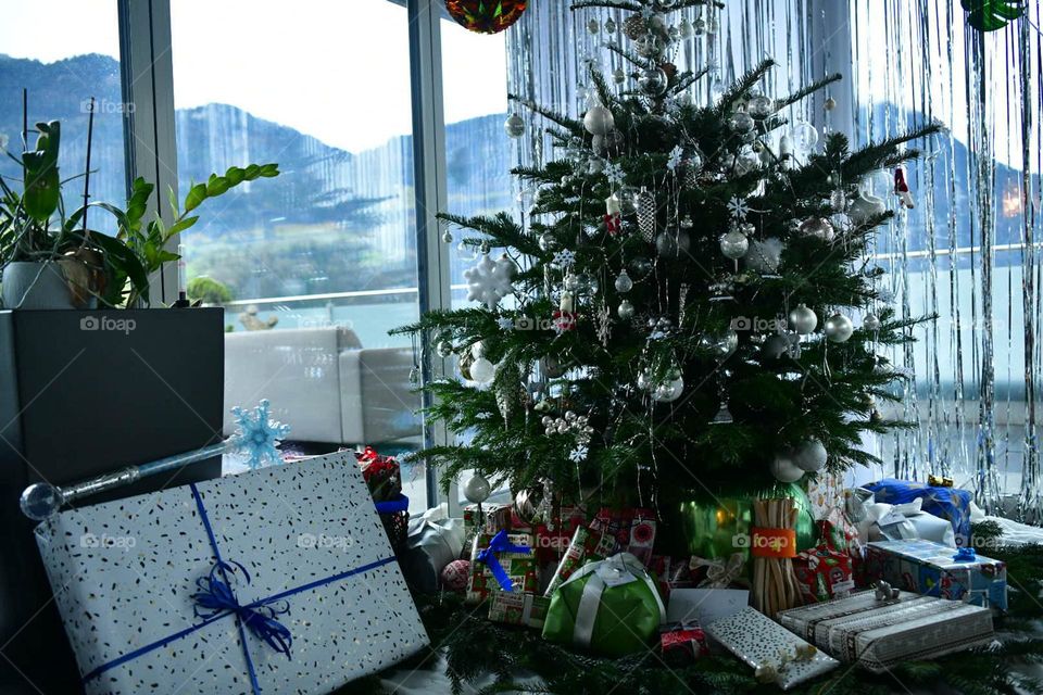 Christmas tree decorated with white toys.  many gifts under the tree