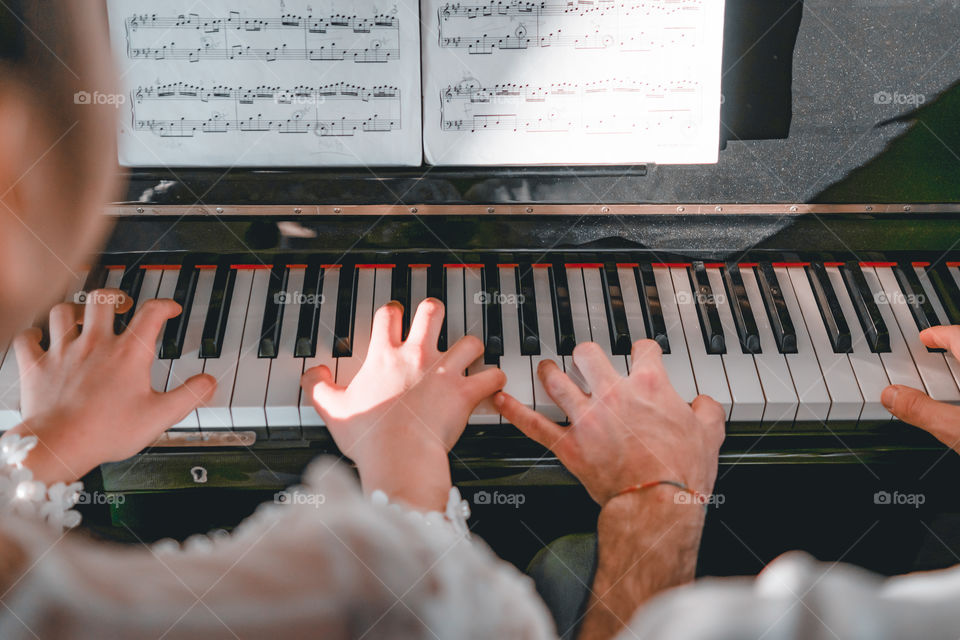 Girl teaches a pupil to play the piano