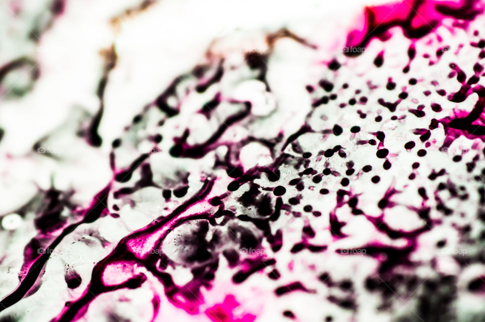 Black and pink refill ink spilled onto the white sink and the ink mixed into abstract blobs and patterns.
